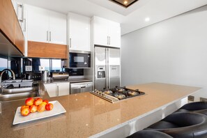 A modern kitchen with white cabinets, stainless steel appliances, and a granite countertop. - Sairia House (La Mercy)