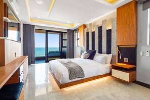 Un dormitorio moderno con una cama grande, una mesita de noche de madera, un estante empotrado y vistas al océano.