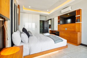 A modern bedroom with a large bed, built-in TV, and a wardrobe. - Sairia House (La Mercy)