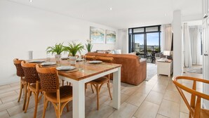 Ein modernes Wohnzimmer mit Essbereich, großen Fenstern und Blick auf die Stadt.