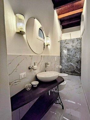 Ein modernes Badezimmer mit einem großen, ovalen Waschbecken, einem Spiegel und einer Dusche mit Marmorwänden.
