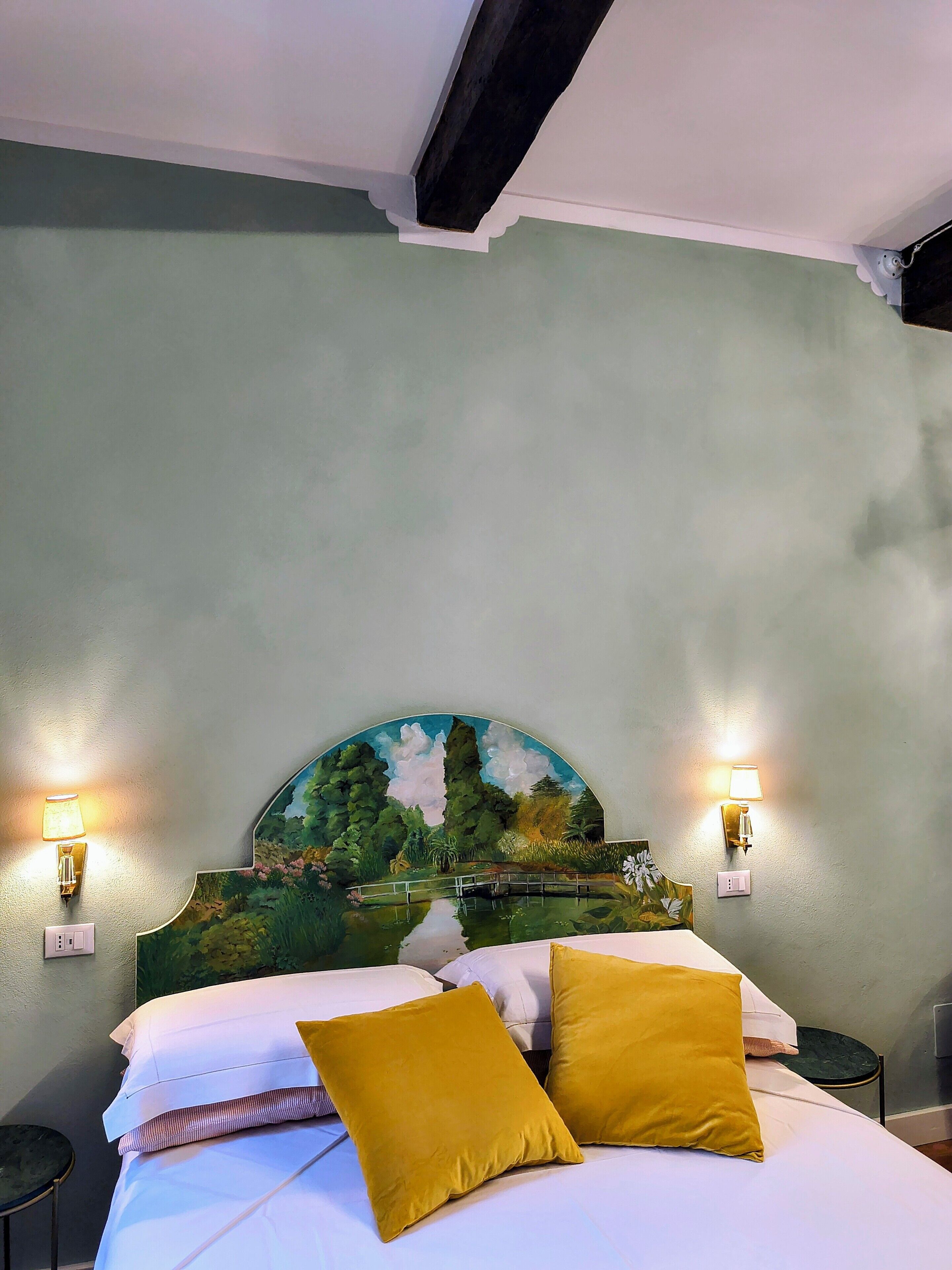Una camera da letto con un letto, due lampade da comodino, un comodino e un quadro raffigurante un paesaggio.