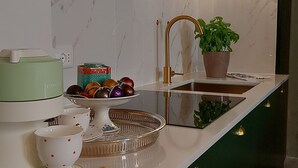Eine moderne Küche mit Marmorfliesenspiegel, einer integrierten Kochinsel, einer Nespresso-Maschine und einem Kronleuchter.