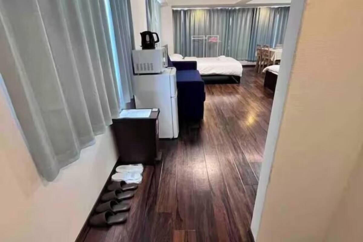 A hotel room with a bed, a desk with a computer, a coffee maker, and a small seating area.