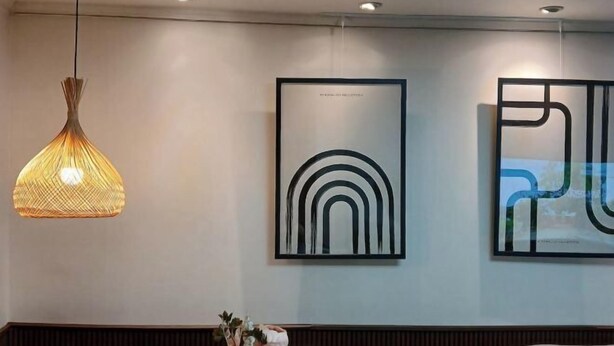 A modern interior with a hanging light fixture, a framed abstract artwork, and a wall-mounted light.
