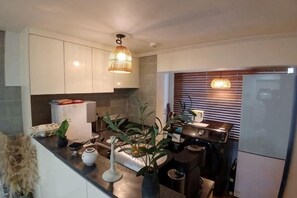 A modern kitchen with white cabinets, a built-in oven, and a refrigerator. There are plants on the counter and a hanging light fixture. - Yongsan, HYBE, Myeongdong, Gwangjang Market, Gyeongbokgung Palace, Luggage Storage Service 8 people (Seoul)