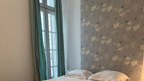 Uma cama de solteiro com estrutura de madeira, colchão branco e uma toalha enrolada na cabeceira.