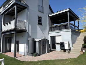 Un bâtiment moderne à deux étages, doté d’un espace extérieur couvert, d’un garage et d’un escalier menant à l’étage supérieur.