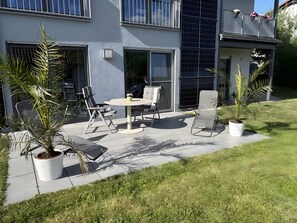 Une terrasse avec des meubles d’extérieur, une table et des plantes en pot.