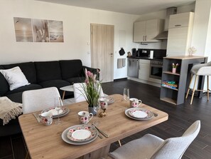Un espace de vie moderne comprenant un coin repas, une cuisine et un canapé noir.