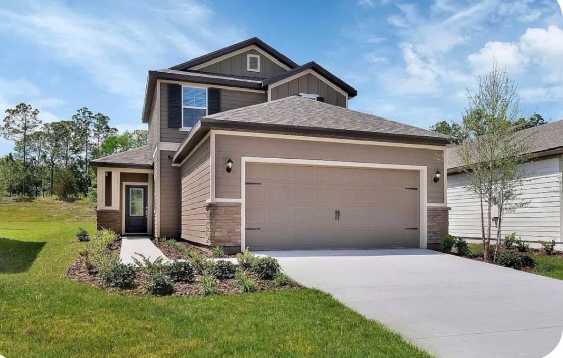 A two-story house with a garage, a front yard with landscaping, and a clear sky.