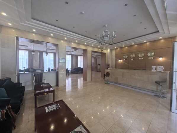 A spacious lobby with a reception desk, seating area, and a chandelier. - Fude Hotel (Tbilisi)