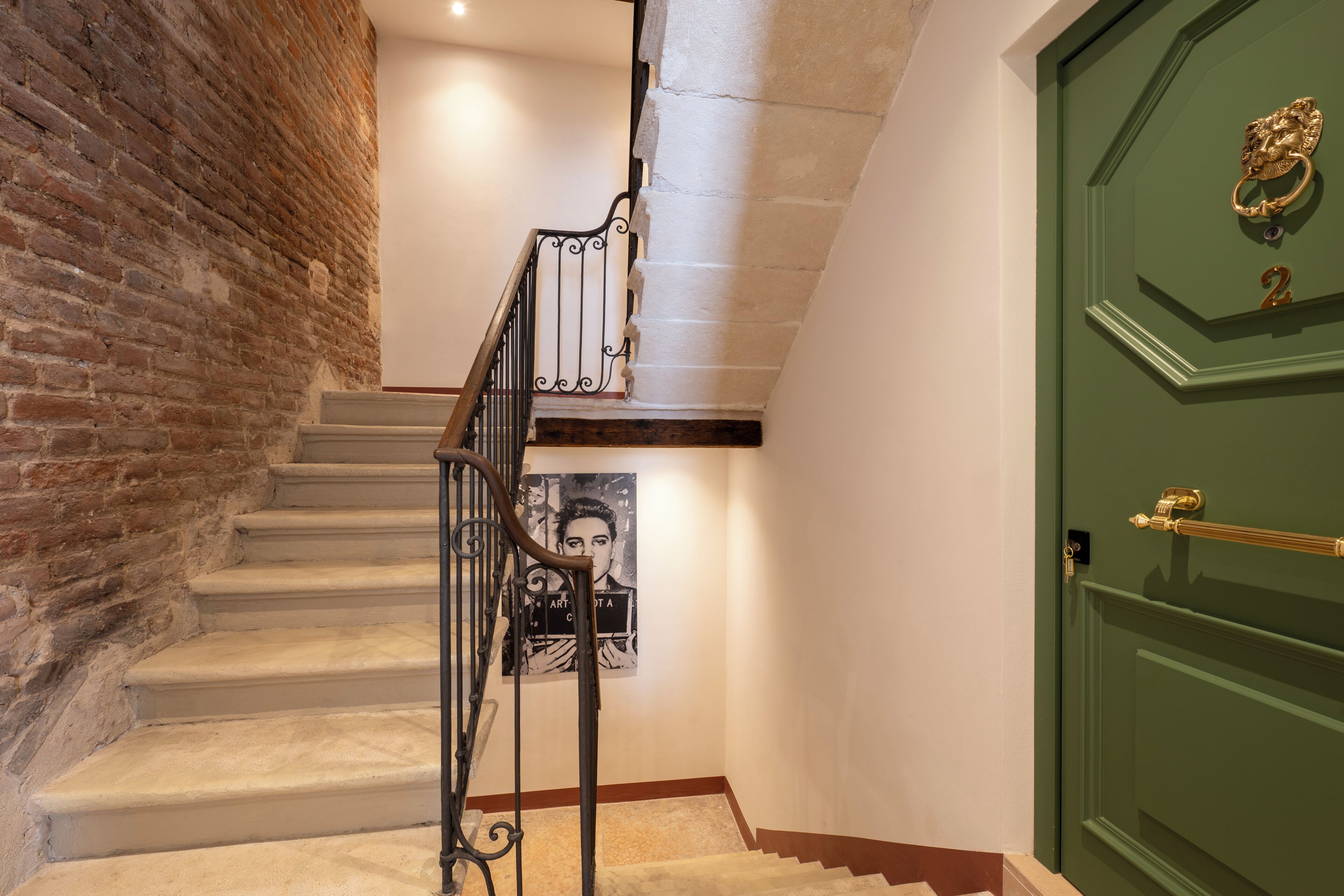 A staircase with a brick wall on one side and a green door on the other.