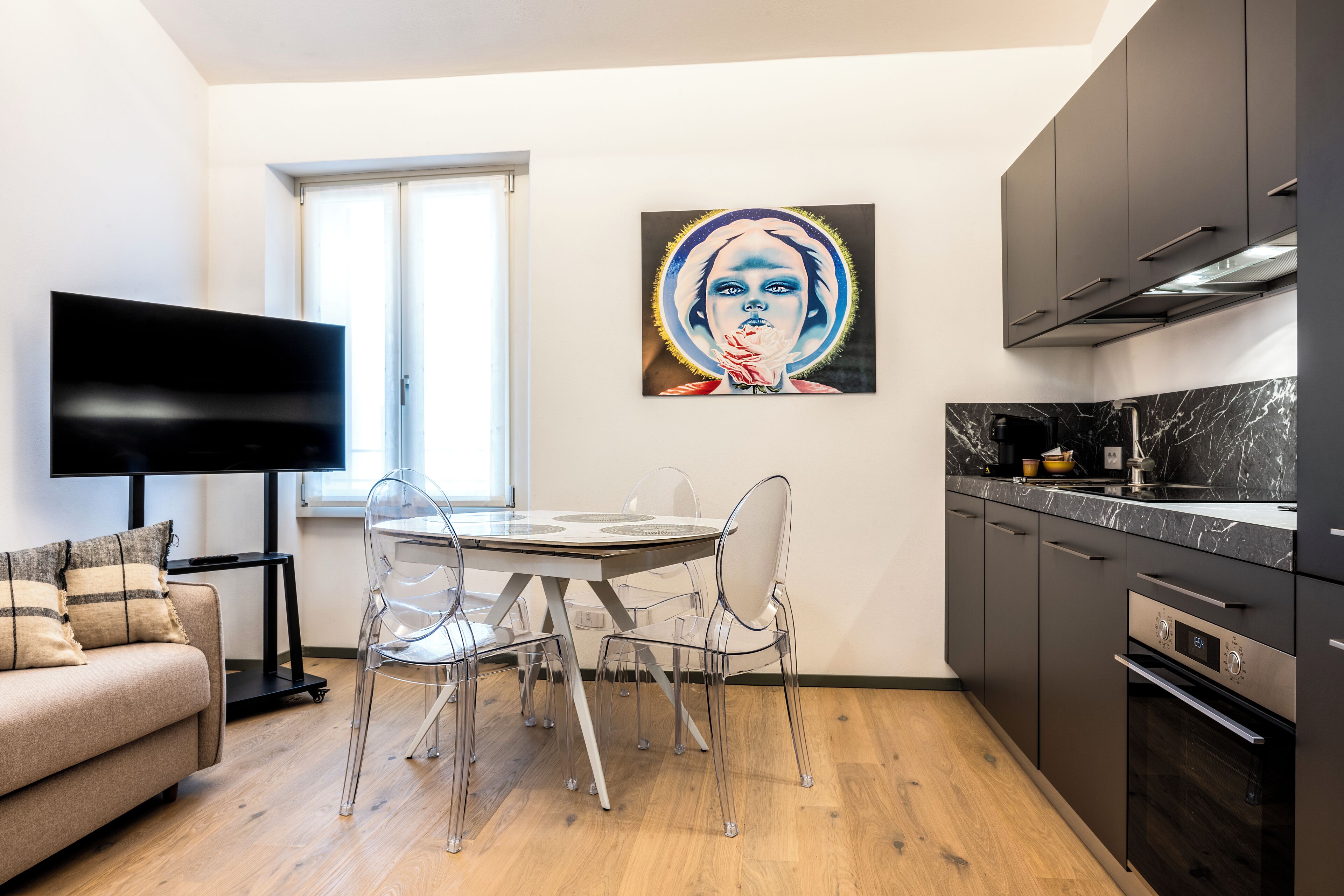 Een moderne keuken met een eettafel, stoelen en een televisie.