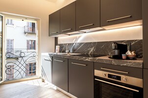 Una cocina moderna con armarios oscuros, encimera de mármol y horno empotrado.