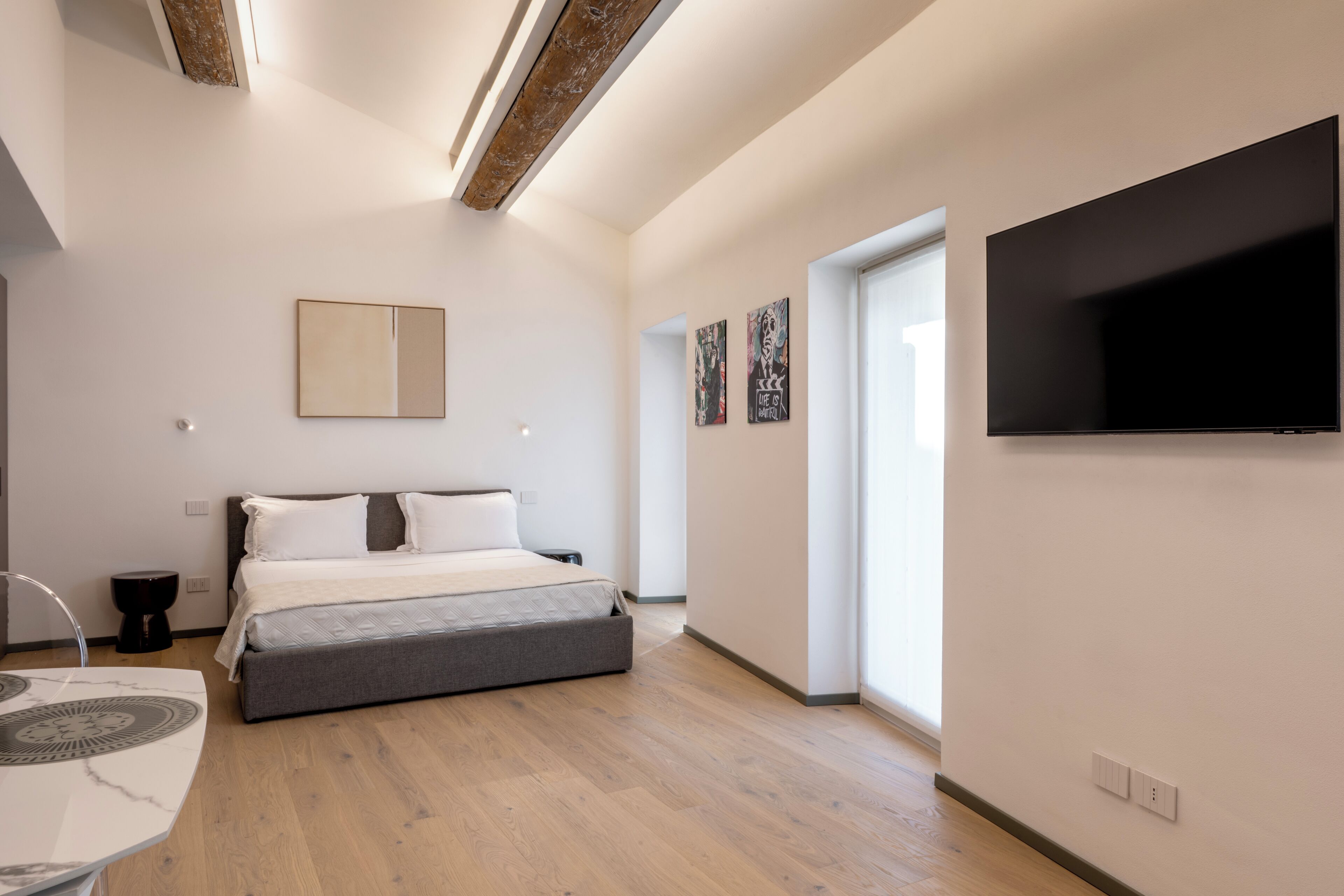 Un dormitorio moderno con cama, televisor de pantalla plana y obras de arte en las paredes.