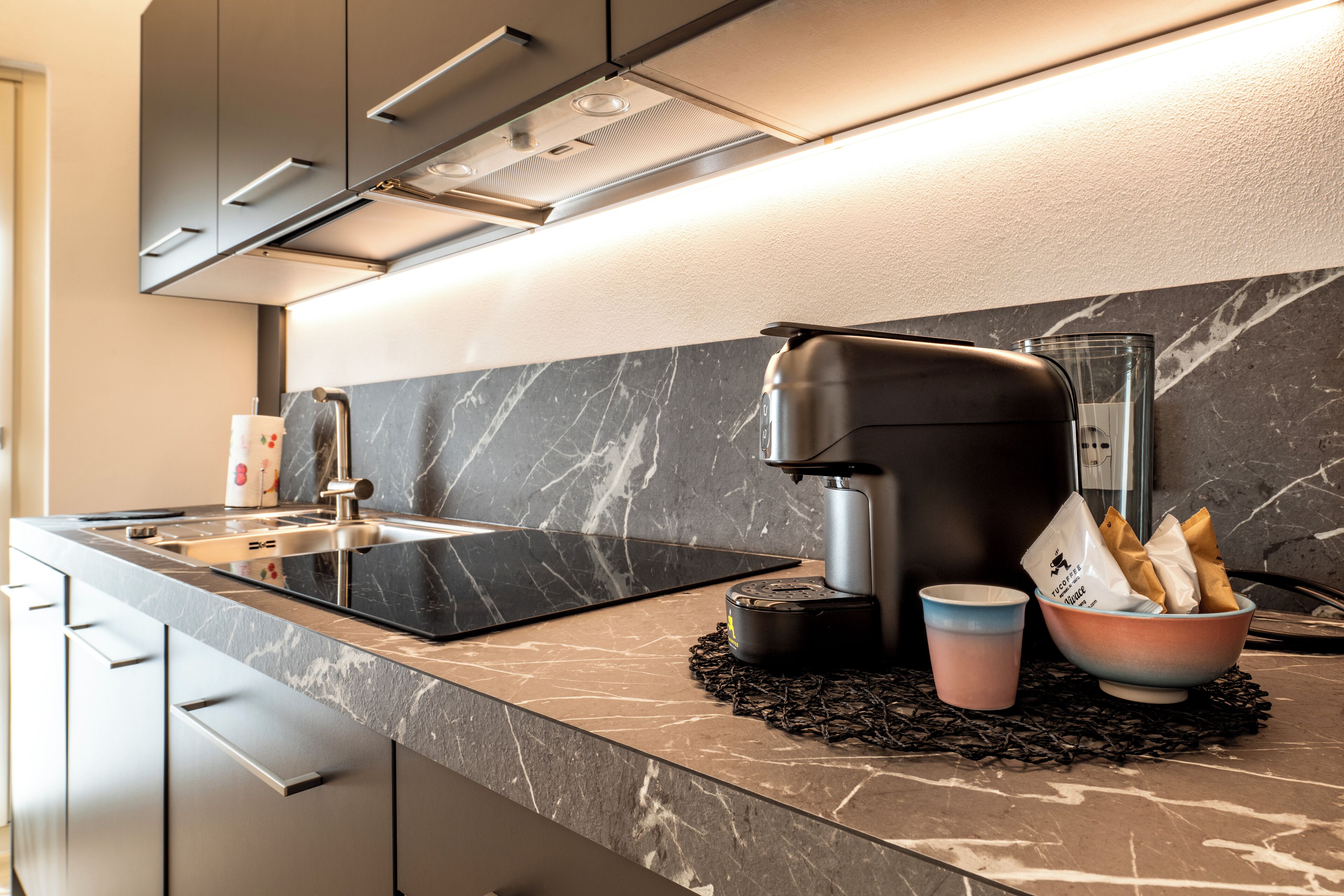 A modern kitchen with a black countertop, stainless steel appliances, and a marble backsplash.