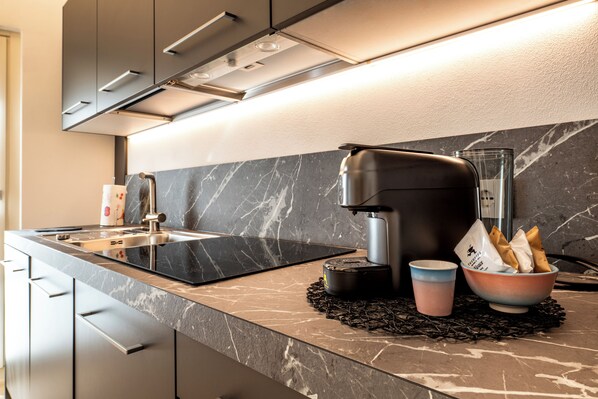 A modern kitchen with a black countertop, stainless steel appliances, and a marble backsplash. - Residenza Wega (Verona)