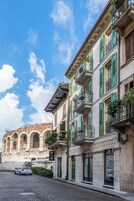 Una calle con edificios históricos, un camino adoquinado y un coche blanco estacionado al costado.