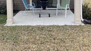 A covered patio with two chairs and a grill, leading to a glass door entrance. - Relax near Historic St. Augustine & Beaches (St. Augustine)
