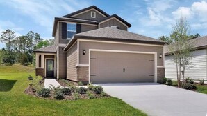 A two-story house with a garage, a front yard with landscaping, and a clear sky. - Relax near Historic St. Augustine & Beaches (St. Augustine)