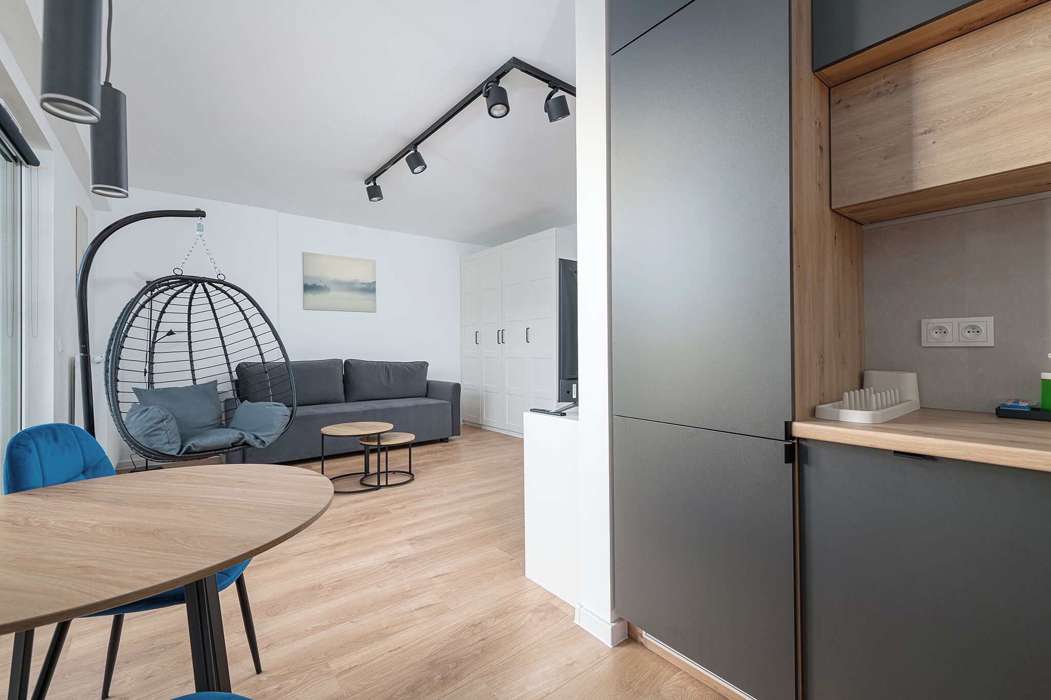 A modern kitchen with a built-in refrigerator, wooden countertop, and hanging lights.