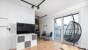 Une cuisine moderne dotée d’un téléviseur encastré, de meubles en bois et d’un coin repas comprenant un fauteuil suspendu et deux chaises.