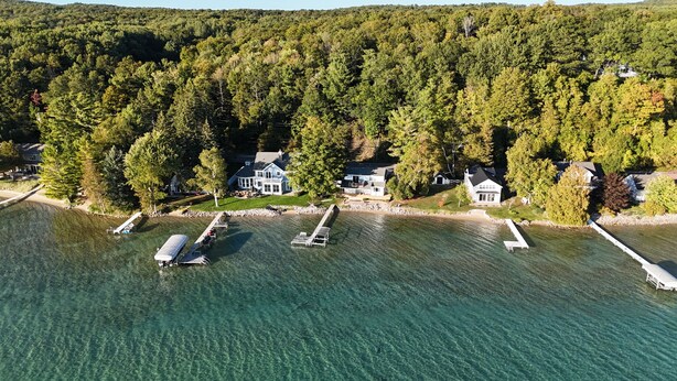 Vue aérienne d’une propriété au bord du lac, avec plusieurs maisons, des quais et une eau cristalline.