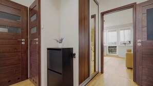 Un apartamento moderno con puertas de madera, un refrigerador negro pequeño y vistas a un balcón con una silla amarilla.