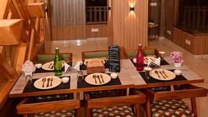 A dining area with wooden tables and chairs, a menu stand, and a view of the outside. - Mystic  Manali (Manali)