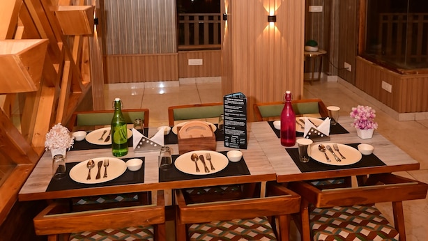 Un comedor con mesas y sillas de madera, un atril para el menú y vistas al exterior.