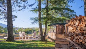 A wooden deck with chairs, a small wooden structure, and a stack of firewood.