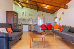 A living area with a sofa, a wooden table, and a kitchen in the background.