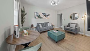 A modern living room with a grey sofa, a round wooden table, and a teal ottoman. - The Luxe Pearl Residences - 8ppl (Columbus)