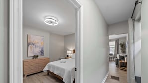 A modern bedroom with a bed, bedside table, lamp, and artwork on the wall. - The Luxe Pearl Residences - 8ppl (Columbus)