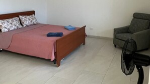 A bedroom with a bed, a chair, and a standing fan. - two-room apartment, mirabilandia (Fosso Ghiaia)