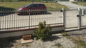 A gated parking area with a red car, a tree, and a building in the background. - two-room apartment, mirabilandia (Fosso Ghiaia)