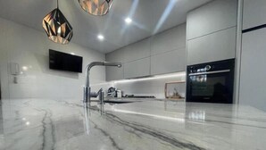 Una cocina moderna con encimera de mármol, grifo de acero inoxidable e iluminación colgante.