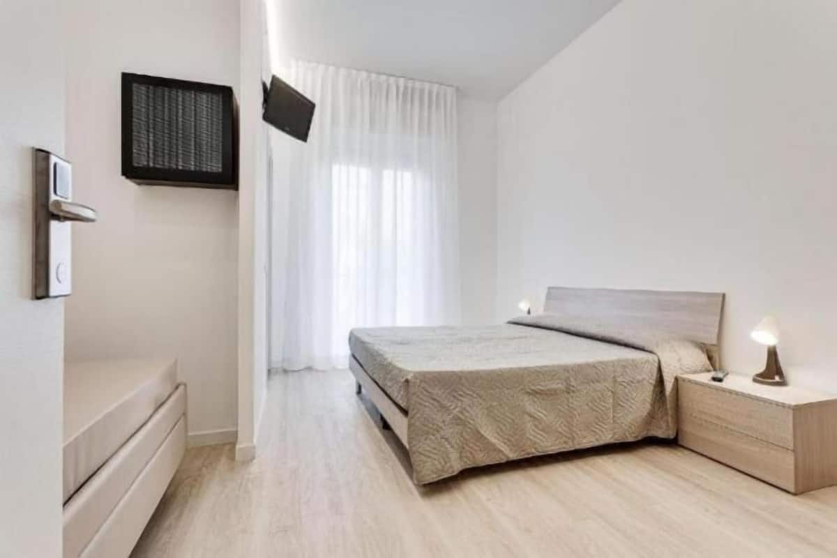 A modern bedroom with a bed, bedside table, and a wall-mounted TV.