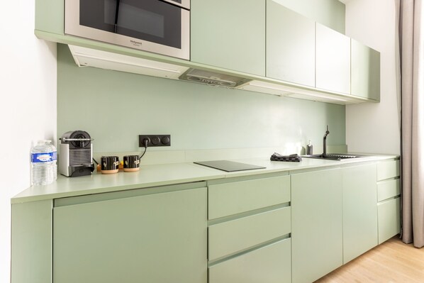 Una cocina moderna con microondas integrado, hervidor y cafetera en la encimera.