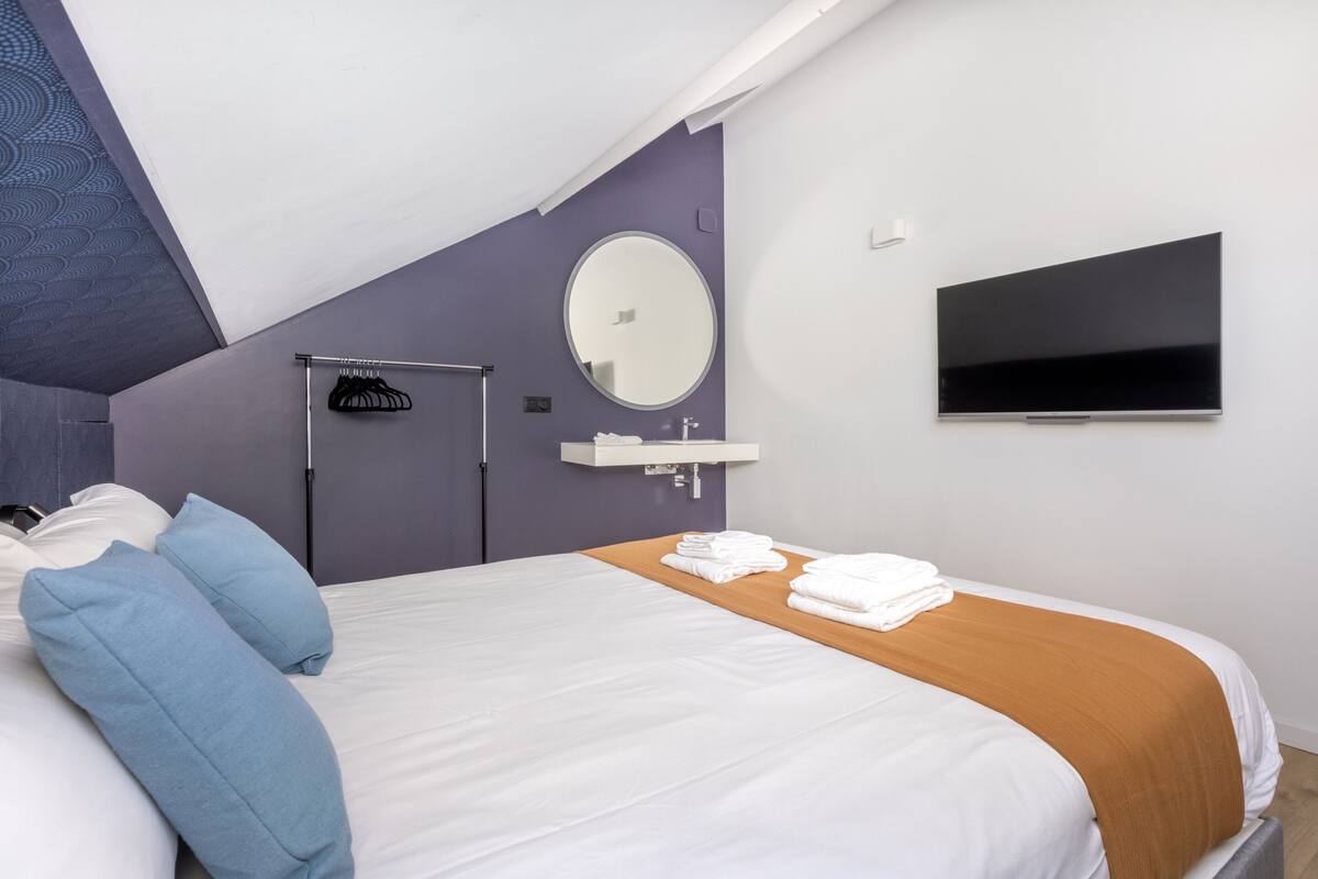 Une chambre d’hôtel moderne équipée d’un grand lit, d’une télévision, d’un miroir et d’un porte-serviettes.