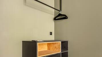 Une pièce moderne avec un bureau sombre, une étagère en bois et un luminaire suspendu.