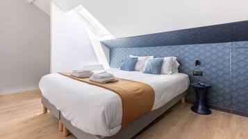 Een moderne slaapkamer met een groot bed, een blauwe accentmuur en een dakraam.