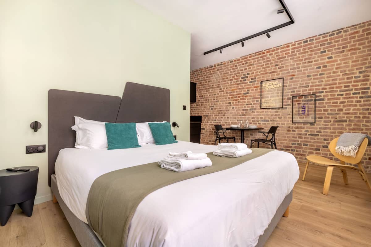 Une chambre d’hôtel moderne avec un grand lit, un mur en briques et un petit coin repas.