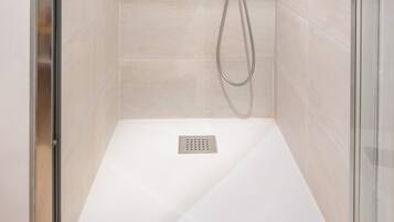 A modern shower with a handheld showerhead and a wall-mounted control panel.