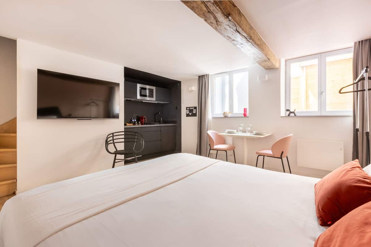 Une chambre d’hôtel moderne équipée d’un lit, d’un bureau, d’une chaise, d’un four à micro-ondes et d’une fenêtre avec des rideaux.