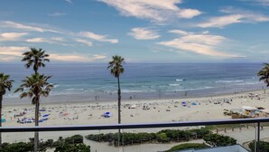 Una playa con palmeras, sombrillas y gente.