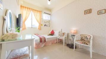 A room with a bed, a desk, a chair, a lamp, and a window with curtains.
