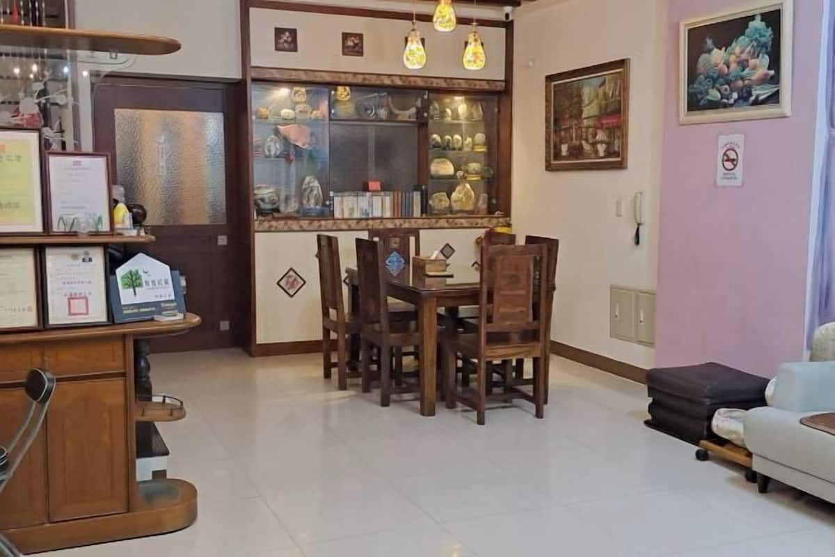 A dining area with a wooden table and chairs, a glass display case with various items, and a wall-mounted telephone.