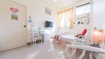 A bedroom with a bed, a desk, a chair, a TV, and a window with curtains.